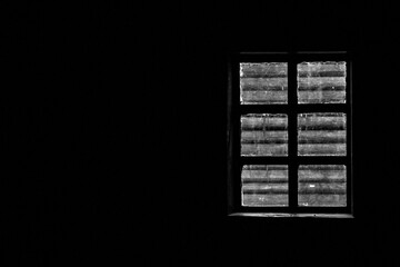 View through the window from inside the room. Window inside a dark room. Through the window of the room you can see the wall of the log house outside. Through the window you can see the log house 