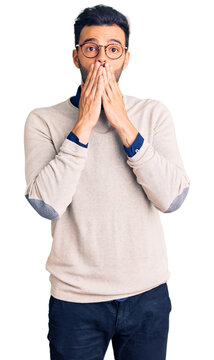 Young handsome hispanic man wearing elegant clothes and glasses shocked covering mouth with hands for mistake. secret concept.