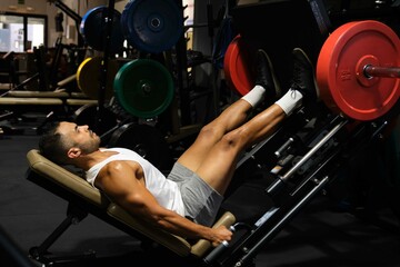 Fototapeta na wymiar Strong Hispanic man doing leg press at a gym.