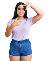 Obraz premium Young beautiful asian girl wearing casual clothes smiling making frame with hands and fingers with happy face. creativity and photography concept.