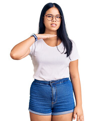 Fototapeta premium Young beautiful asian girl wearing casual clothes and glasses cutting throat with hand as knife, threaten aggression with furious violence