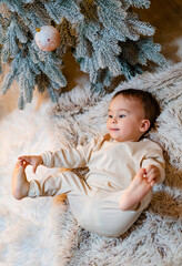 A Beautiful Baby on a Cozy Rug, Surrounded by a Festive Christmas Tree. A baby laying on a rug next...