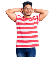 Fototapeta premium Handsome latin american young man wearing casual clothes and glasses relaxing and stretching, arms and hands behind head and neck smiling happy