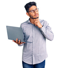 Handsome latin american young man working using computer laptop serious face thinking about...