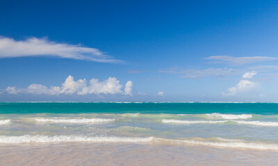 Obraz premium Caribbean Sea shore waves are under blue sky on a sunny day