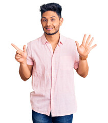 Handsome latin american young man wearing casual summer shirt showing and pointing up with fingers number seven while smiling confident and happy.