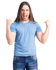 Young adult man with long hair wearing casual clothes screaming proud, celebrating victory and success very excited with raised arms