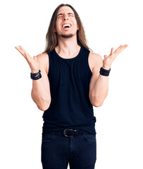 Young adult man with long hair wearing rocker style with black clothes and contact lenses...