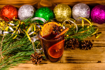 Cup of mulled wine with cinnamon, christmas decorations and fir tree branches on wooden table