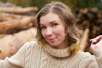 smiling woman  in front of wooden logs.