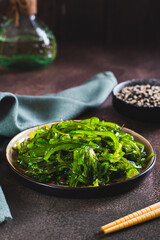 Traditional fresh seaweed and sesame salad on a plate on the table vertical view