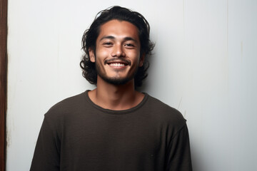 Man with long hair smiling in front of white wall. Perfect for portraying happiness and positivity in various settings.