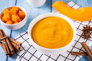 Organic pumpkin puree in a bowl, pumpkin and spices for cooking on the table