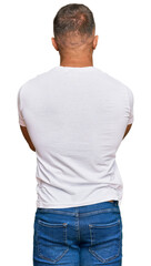 Handsome muscle man wearing casual white tshirt standing backwards looking away with crossed arms