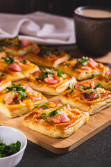 Mini pizza with sausages, tomatoes, cheese and herbs on a wooden board on the table vertical view