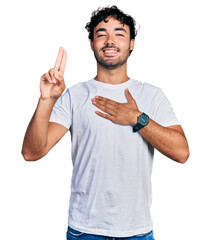 Hispanic young man with beard wearing casual white t shirt smiling swearing with hand on chest and...