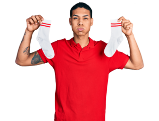 Young hispanic man holding socks puffing cheeks with funny face. mouth inflated with air, catching air.