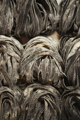 Top view of fresh homemade traditional italian pasta. Uncooked black tagliatelle with flour.