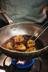 Chef cooking tortelloni with wine sauce on a hot pan. Authentic italian restaurant.