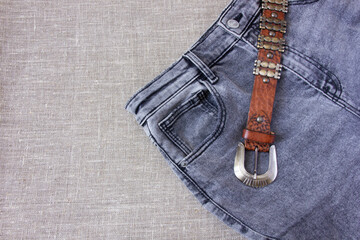 Brown leather belt and gray burlap jeans