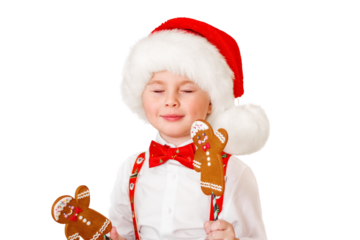 A little boy in a Santa hat holds Christmas gingerbread cookies in his hands. The child smiles with his eyes closed. Isolated close-up portrait.