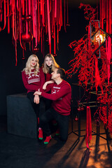 Beautiful cheerful family dressed in New Year's red clothes in an atmospheric photo studio with a stylish festive interior in red colors.