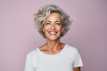 A woman with gray hair is smiling and wearing a white shirt