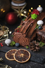 Traditional  French Christmas chocolate dessert  BûchedeNoël (Yule log). Christmas festive pastry in the shape of a log on the dark concrete background