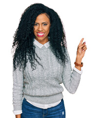 Middle age african american woman wearing casual clothes with a big smile on face, pointing with hand finger to the side looking at the camera.