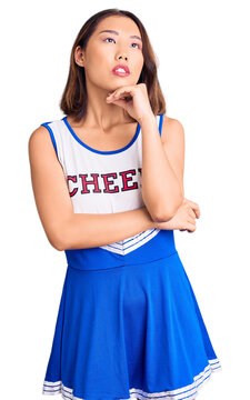 Young beautiful chinese girl wearing cheerleader uniform with hand on chin thinking about question, pensive expression. smiling and thoughtful face. doubt concept.