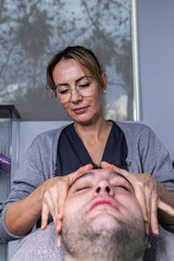 Obraz premium Vertical photo of a woman giving a facial massage to a client in a beauty salon.