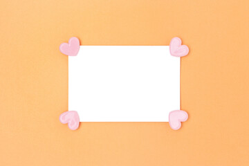 Empty white paper mockup with pink clips in a hearts shape on a gold glittering background. Festive composition.