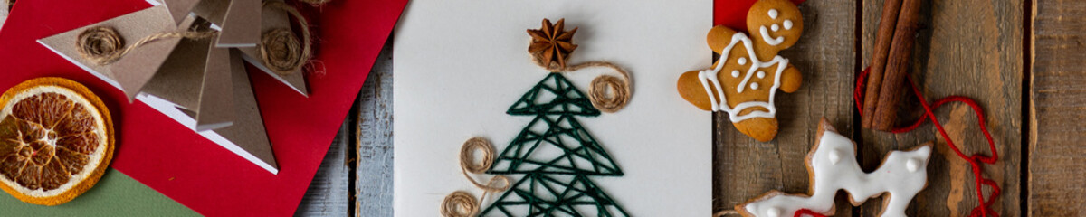 Handmade craft Christmas card with paper fir tree. Gingerbread cookies, marshmallow, cinnamon...