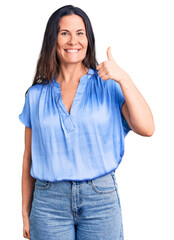 Young beautiful brunette woman wearing casual t-shirt smiling happy and positive, thumb up doing excellent and approval sign