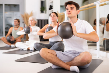 Pilates group workout for a healthy lifestyle. Strong men and women have fun doing sports exercises with ball.