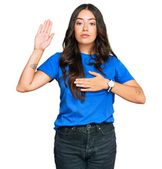 Beautiful brunette young woman wearing casual clothes swearing with hand on chest and open palm,...
