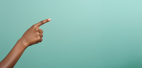 A woman's hand elegantly points to an empty space on a turquoise background, inviting creativity and design possibilities