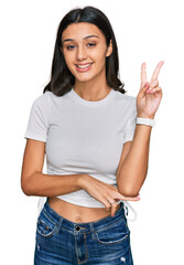 Young hispanic girl wearing casual white t shirt smiling with happy face winking at the camera...