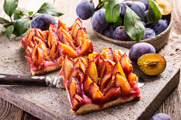 Traditional German plum cake with sliced plums served as close-up on a design stone tray