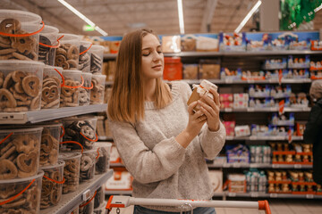 Stack of Chocolate Santa Clauses. Christmas time. A young woman chooses a gift set for Christmas to a child on a supermarket shelf. - obrazy, fototapety, plakaty