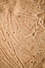 Close-up photo of light brown cream with bubbles on the surface