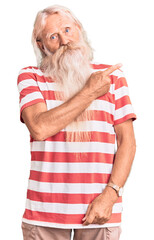 Old senior man with grey hair and long beard wearing striped tshirt pointing with hand finger to the side showing advertisement, serious and calm face