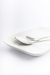 Spoon and fork on white plate on white background, High Key Photography