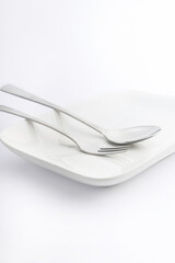 Spoon and fork on white plate on white background, High Key Photography