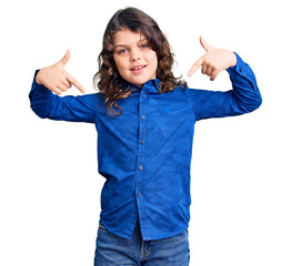 Cute child with long hair wearing casual clothes looking confident with smile on face, pointing...