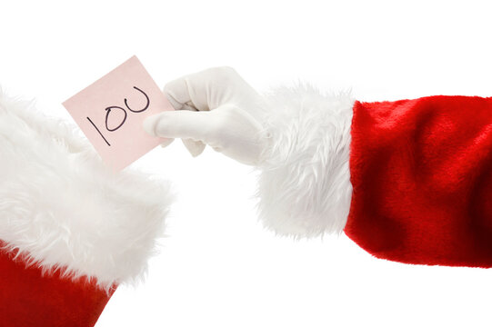 Santa Claus placing an IOU note into a Christmas Stocking isolated