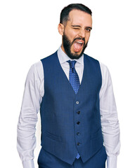 Young man with beard wearing business vest winking looking at the camera with sexy expression, cheerful and happy face.