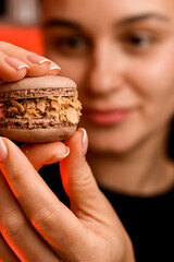 Smiling pastry chef holding a brown macaroon decorated with cornflakes close-up