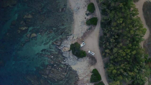 Aerial drone top view of camper vans wild camping near Capo Ferrato cape on the coast of Sardinia, Italy at sunset