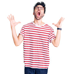 Young hispanic man wearing casual clothes crazy and mad shouting and yelling with aggressive expression and arms raised. frustration concept.